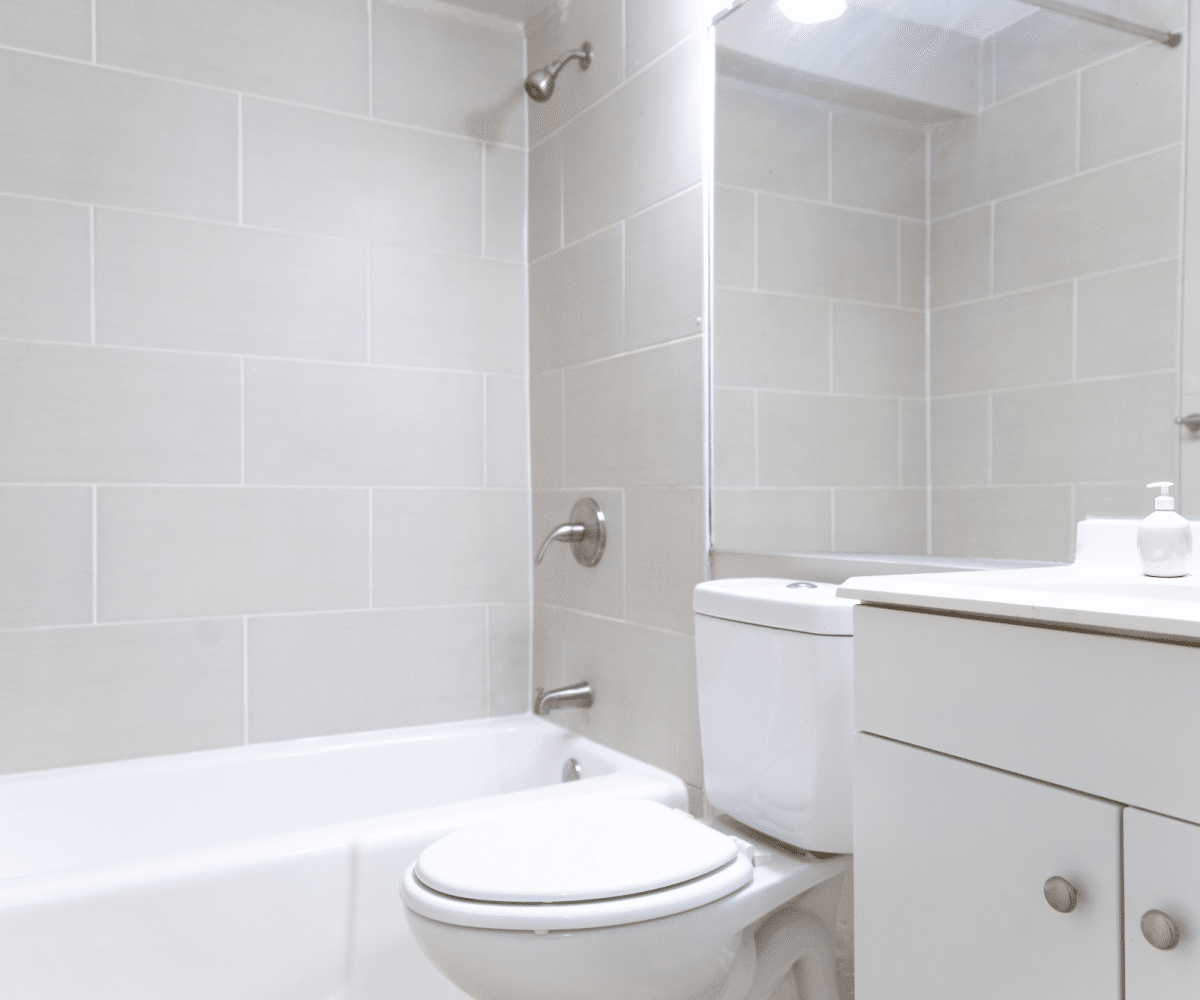Tiled bathroom, bathtub and white toilet.