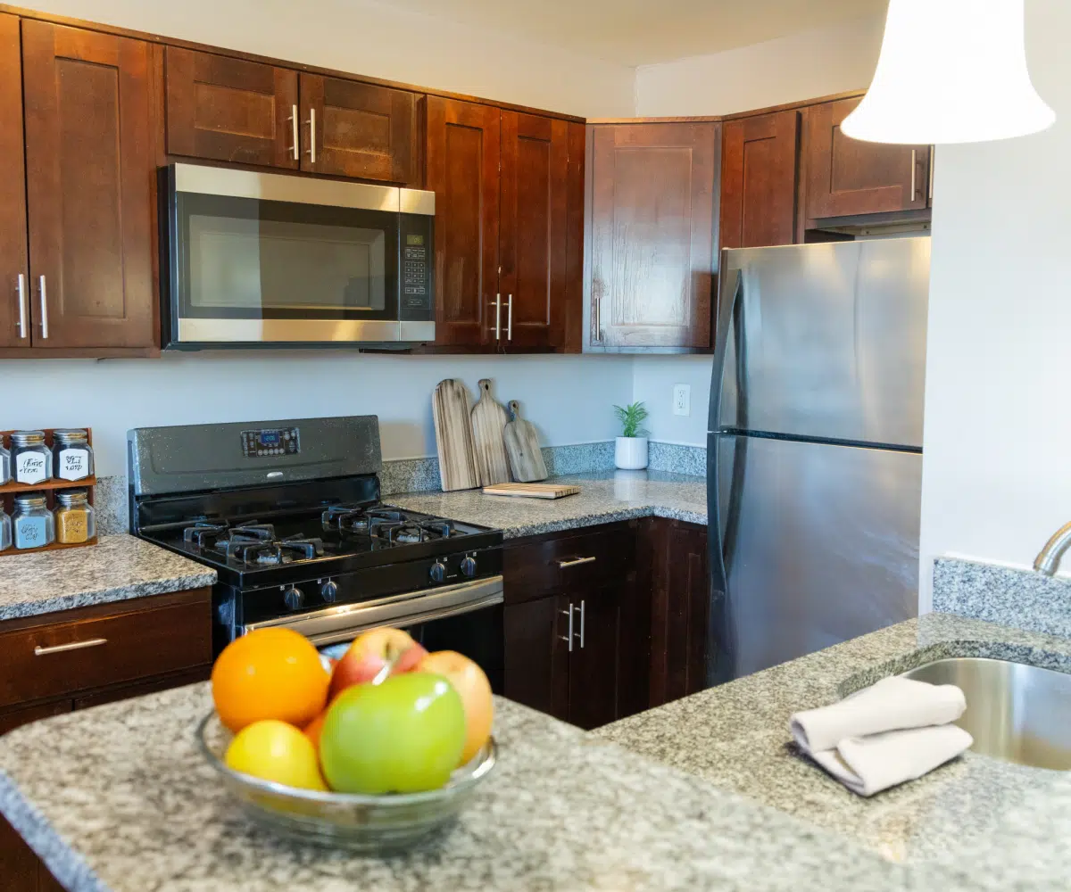Kitchen with wood cabinets, hanging lights, black stove, microwave, and fridge.