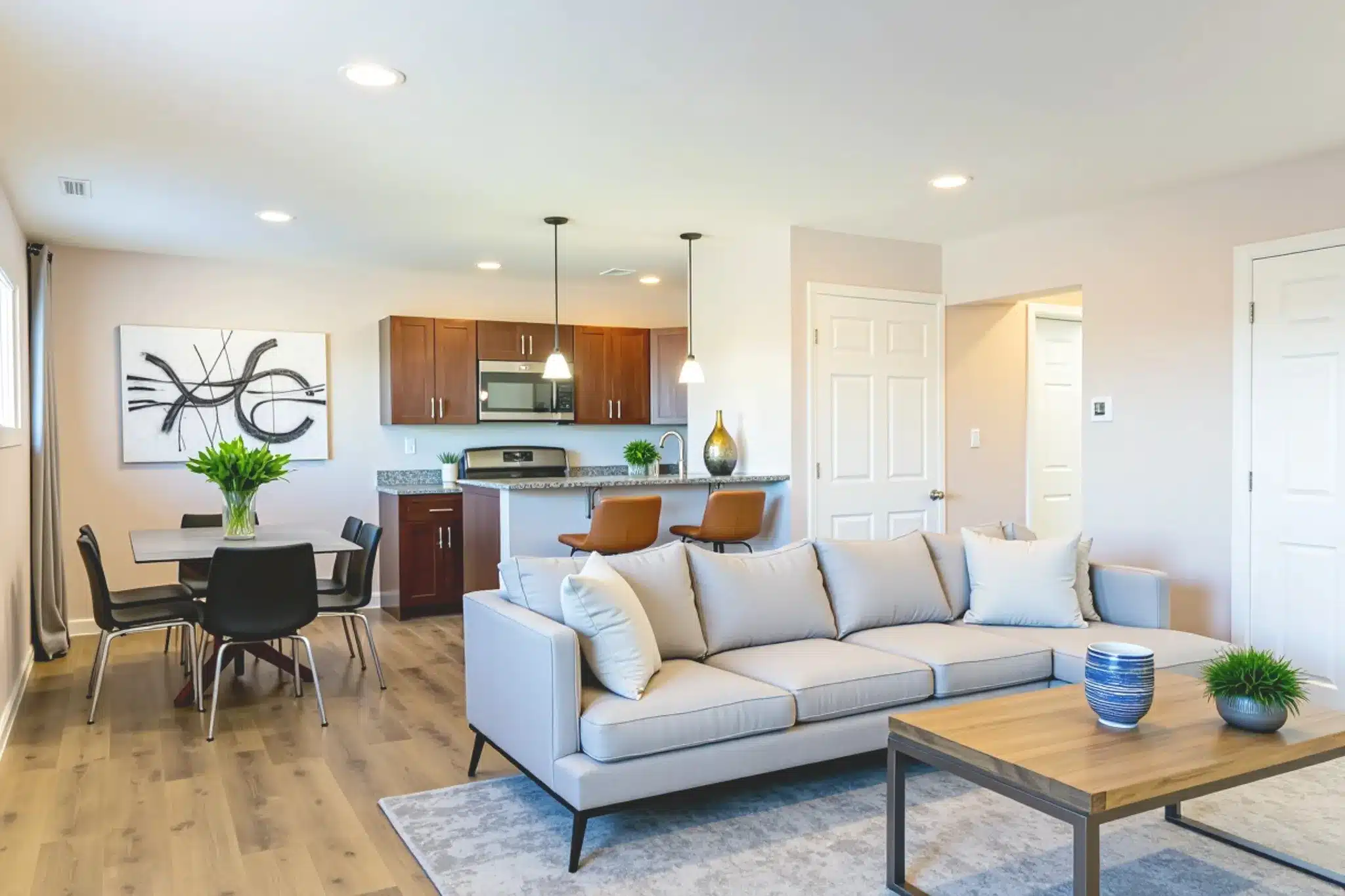 Open plan living room kitchen with kitchen cabinets, counter and grey sofa.