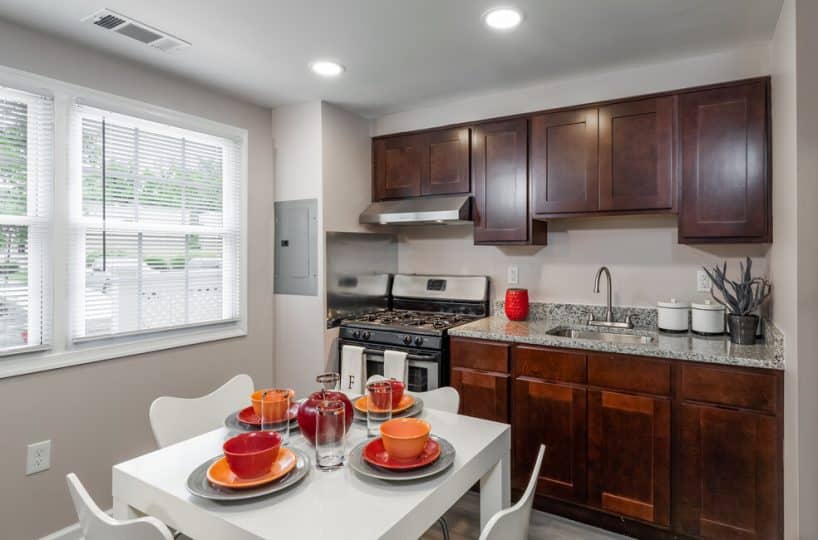 Kitchen with black stove, wood cabinets, white kitchen table and white chairs.