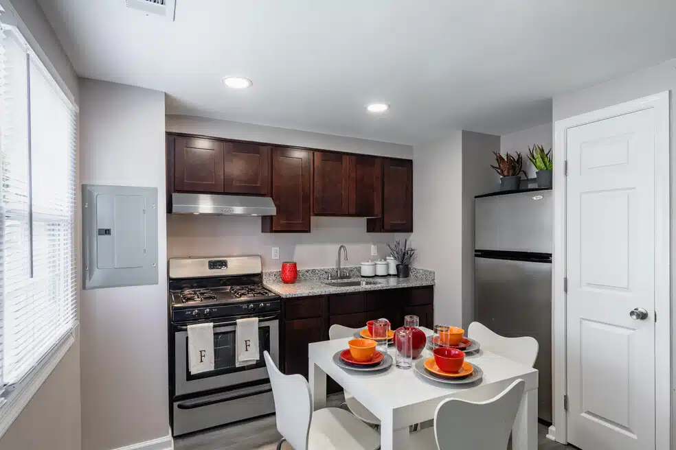 Modern kitchen with stainless steel sink, granite countertops, oven, fridge, white kitchen table, and chairs.