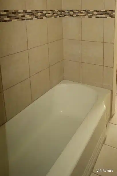 White bathtub with beige tiles.