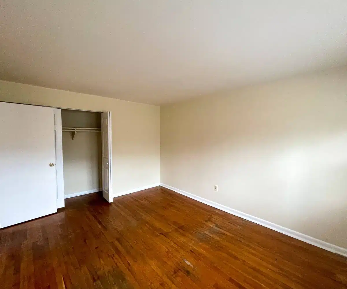 An empty bedroom with hardwood floors and a closet with bifold doors.