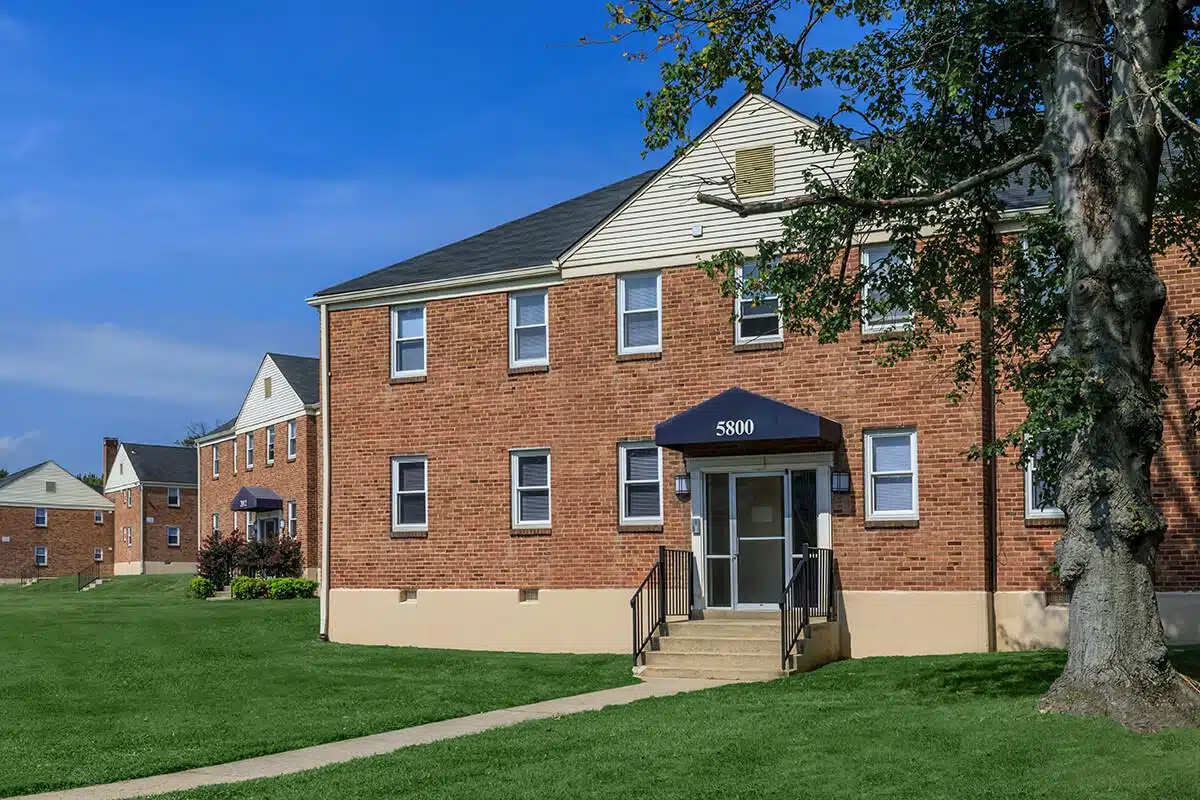 Park Raven Apartments building with a tree and green lawn in front of it.