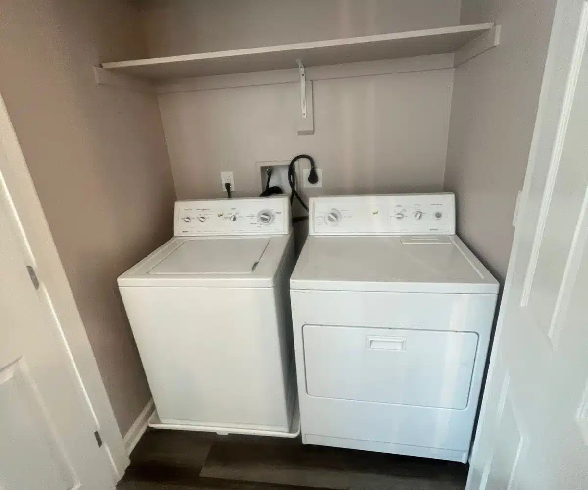 White washer, dryer and shelf located above them.