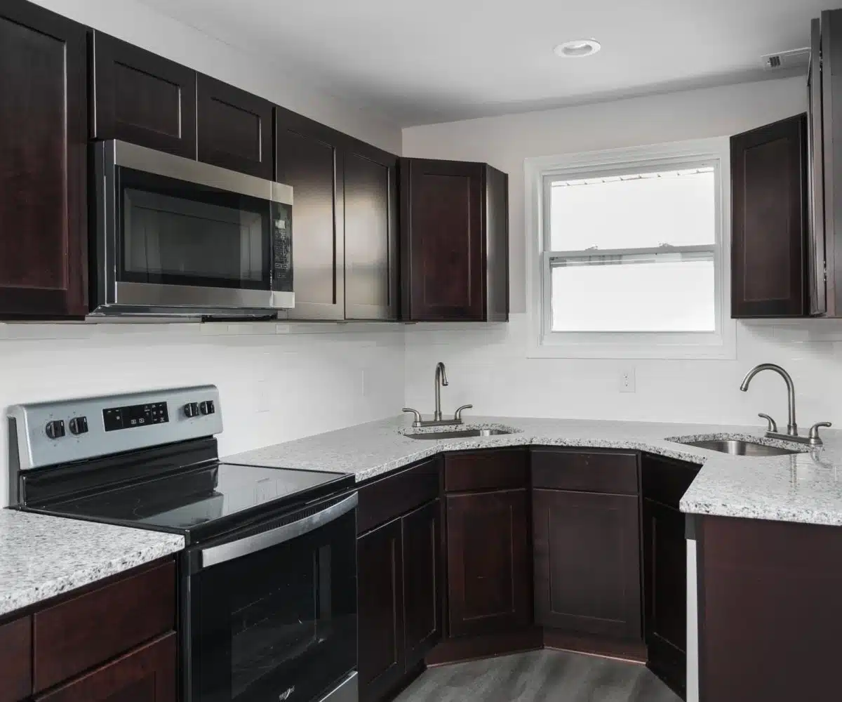 Bancroft Court kitchen with two stainless sinks, wood cabinets, stainless steel oven and microwave.