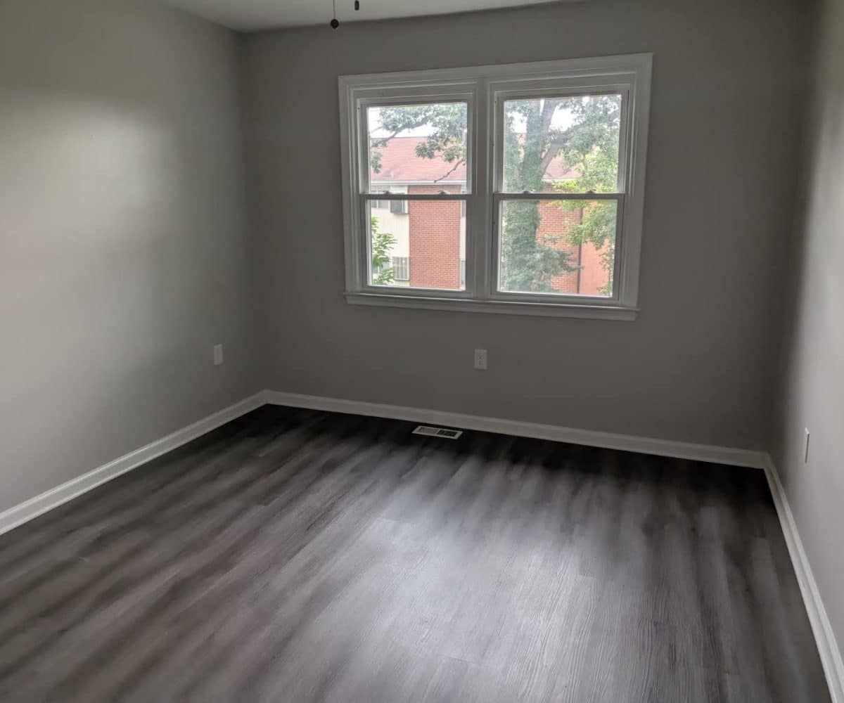 Alameda Townhomes bedroom with two wndows and grey flooring.