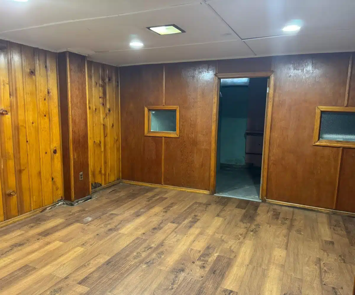 Basement with hardwood floors, wood paneling and ceiling lights.
