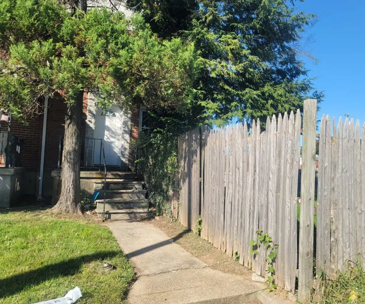 Redbrick townhome with a concrete front path leading to the white front door.