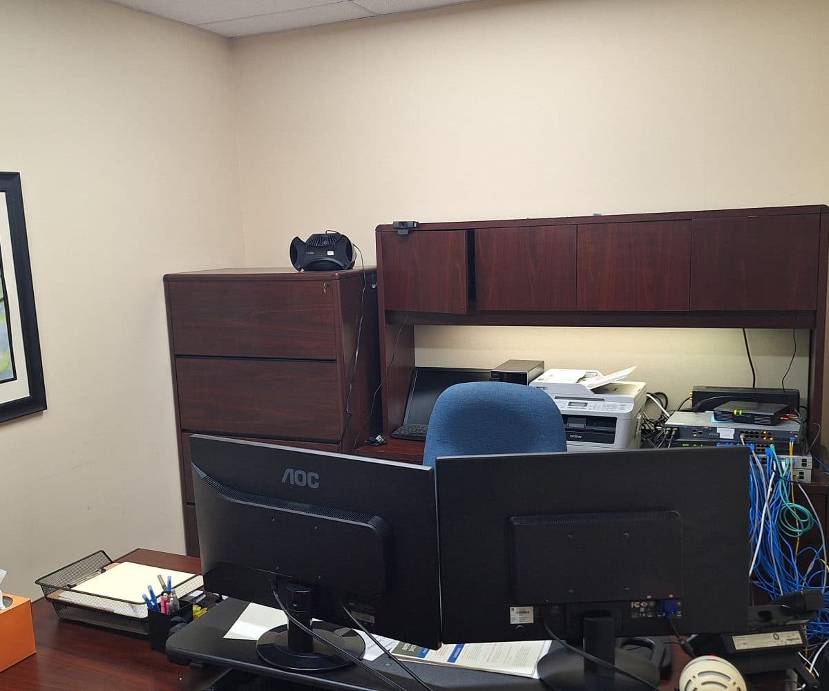 Seton office with desk, computer, printer and wood shelves.