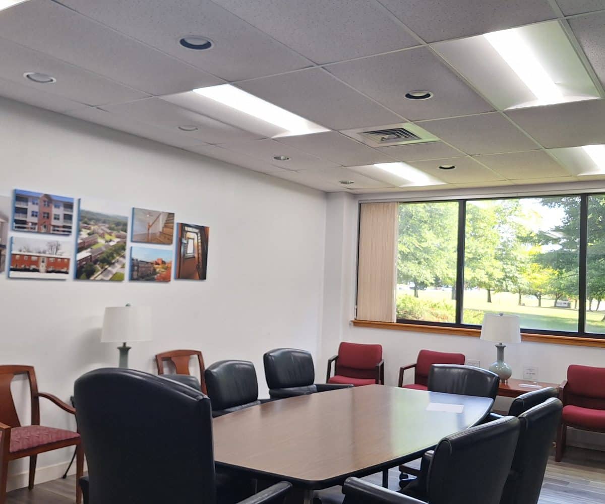 Office conference room with red and black chairs and large picture window with view of trees.