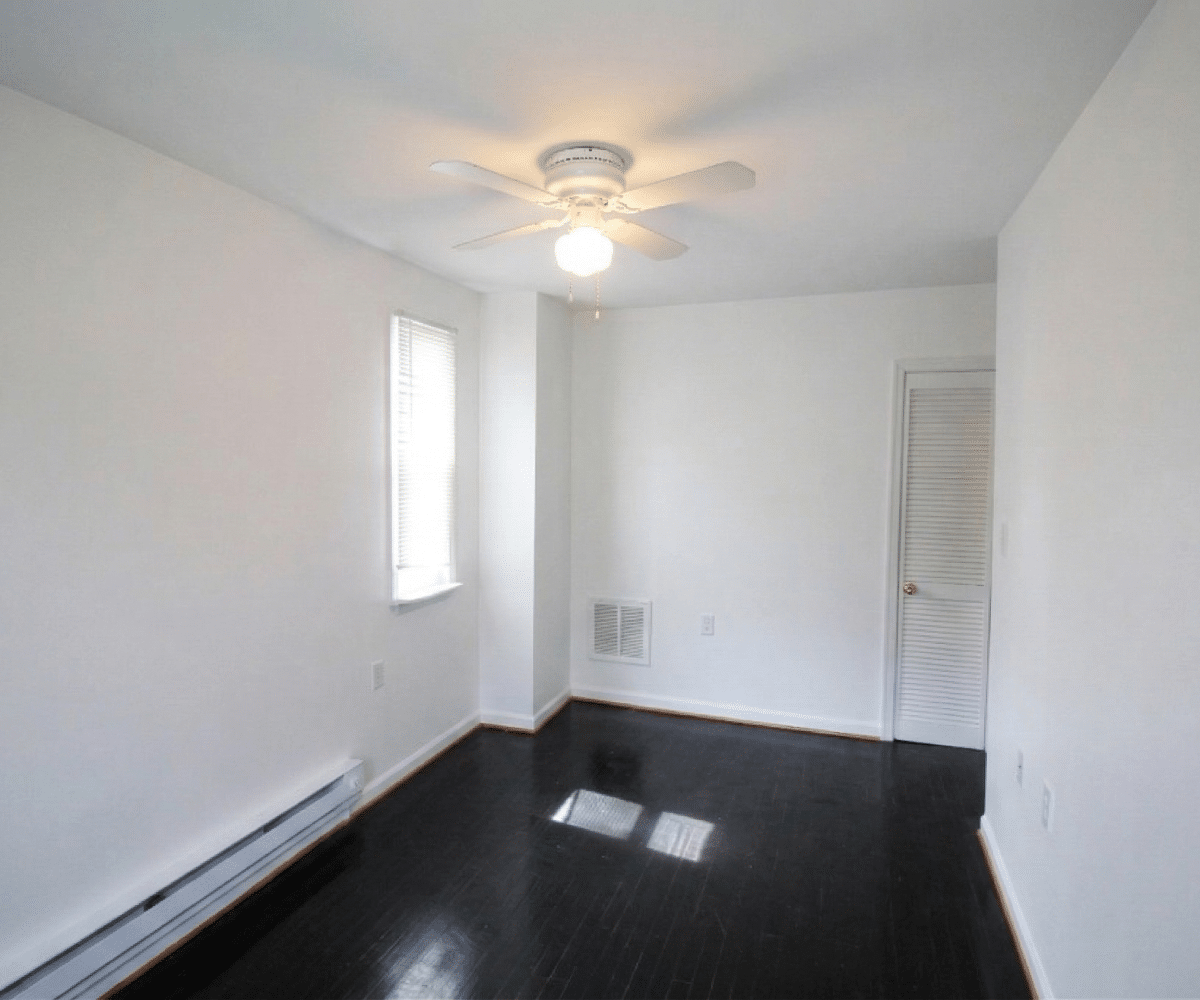 Living room with hardwood flooring and ceiling fan.