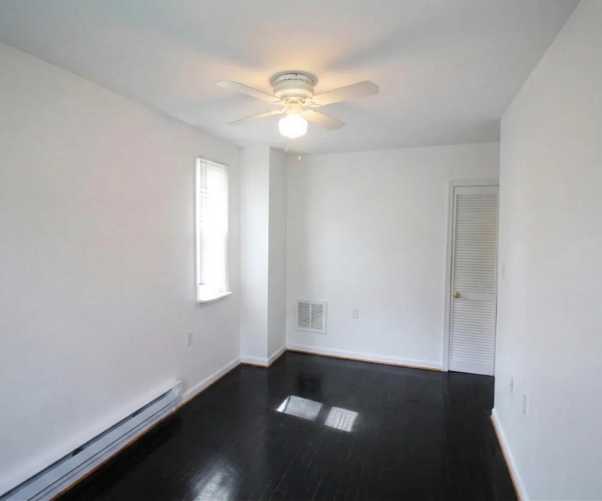 Living room with hardwood flooring and ceiling fan.